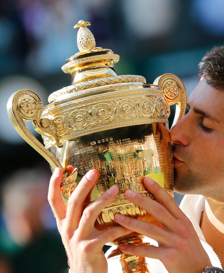 Novak Djokovic of Serbia kisses the trophy after defeating Roger Federer of Switzerland in the men's singles final match at the All England Lawn Tennis Championships in Wimbledon, London, Sunday July 6, 2014.(AP Photo/Ben Curtis)