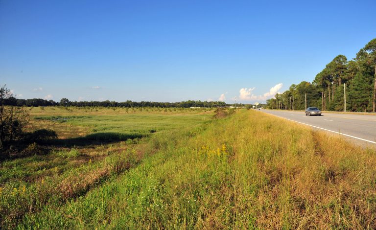 Traffic passes along Newton Rd. beside the proposed 80-acre site for the Sabal Trail pipeline compressor station in Albany, Ga., on Thursday, Oct. 9, 2014. The site, which is opposed by local residents, sits directly across the road from a water treatment plant. (AP Photo/Todd Stone)