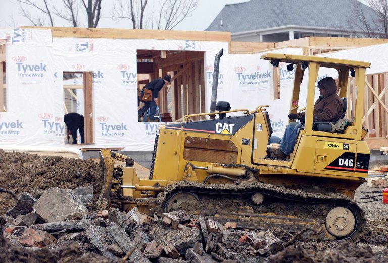 In this Friday, March 28, 2014 photo, Lou Severino moves dirt with a Caterpillar dozer around a home under construction in Pepper Pike, Ohio. Caterpillar reports quarterly earnings on Thursday, April 24, 2014. (AP Photo/Tony Dejak)