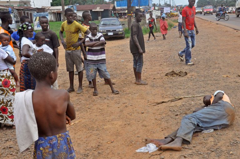 People stand around a man, right, suspected of suffering from the Ebola virus in a main street and busy part in Monrovia, Liberia, Friday, Sept. 12, 2014. A Western Kentucky University student has developed a way to track the Ebola virus outbreak. Armin Smailhodzic (smile-HO'-chih-itch) developed a smartphone app that uses Twitter data to track the virus. Western says the app could predict the spread of the virus.(AP Photo/Abbas Dulleh)