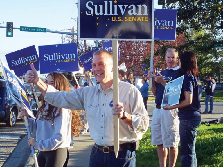 Dan Sullivan, candidate for the Republican candidate for election to the U.S. Senate, waves signs along a busy street on the morning of Alaska's primary election Tuesday, Aug. 19, 2014, in Anchorage, Alaska. (AP Photo/Becky Bohrer)