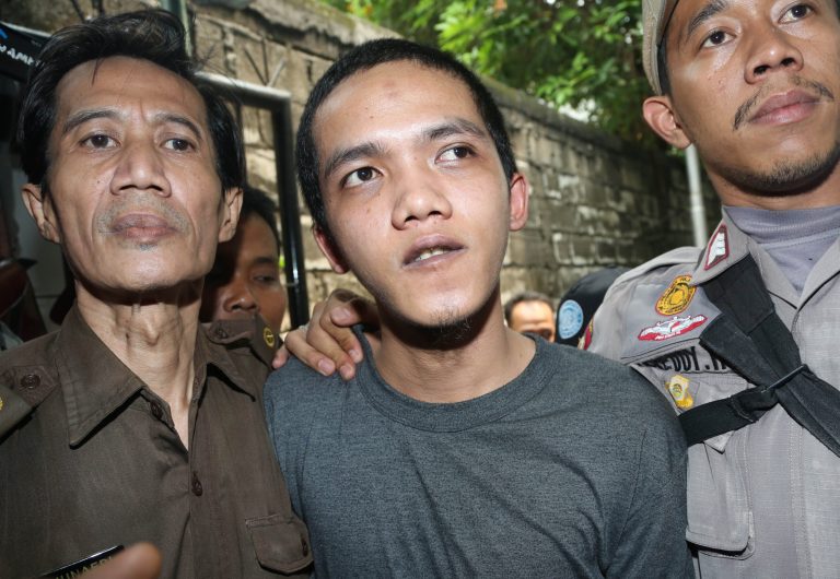 Child sexual abuse suspect Agun Iskandar, center, is escorted by security officers upon arrival for his trial at district court in Jakarta, Indonesia, Tuesday, Aug. 26, 2014. The first of five janitors accused of raping a kindergartner in a bathroom at a prestigious international school went on trial Tuesday. (AP Photo/Tatan Syuflana)