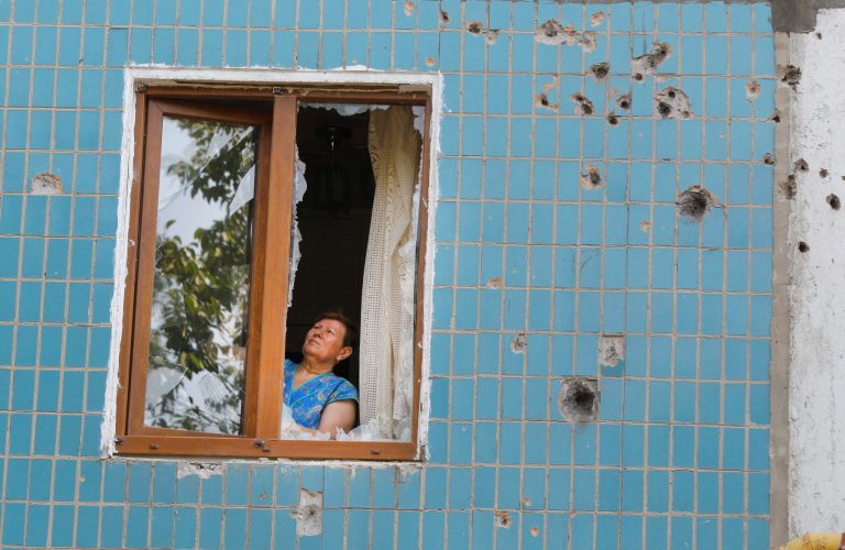 A local woman works on her window after shelling in Donetsk, eastern Ukraine, Friday, Aug. 8, 2014. At least three civilians have been killed and another 10 wounded in overnight shelling of the main rebel stronghold in eastern Ukraine besieged by government forces, officials said. (AP Photo/Sergei Grits)
