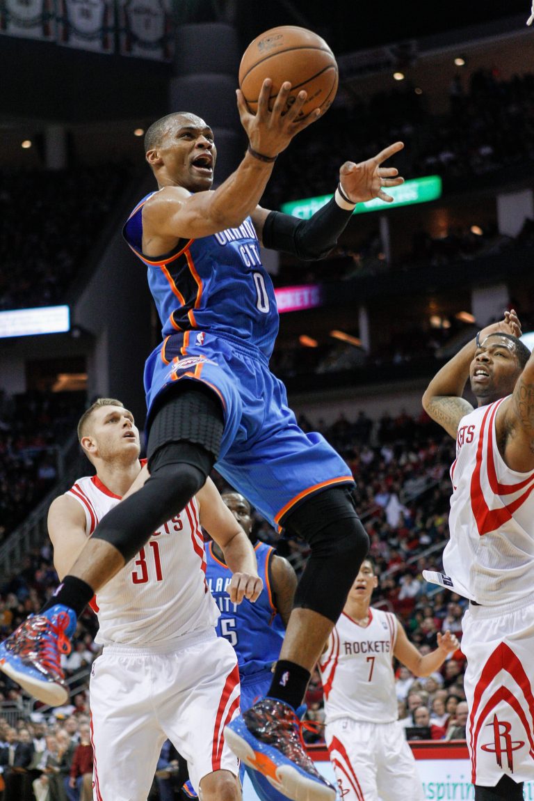   Oklahoma City Thunder guard Russell Westbrook (0) drives to the basket for a layup past Houston Rockets center Cole Aldrich (31) and forward Marcus Morris, right, during the first half of an NBA basketball game, Saturday, Dec. 29, 2012, in Houston. (AP Photo/Bob Levey)  