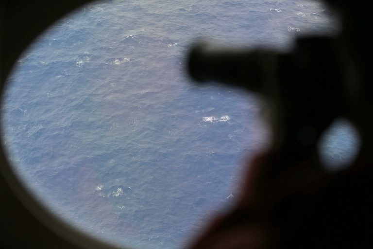 FILE - In this April 1, 2014 file photo, an observer on a Japan Coast Guard Gulfstream aircraft takes photos out of a window while searching for the missing Malaysia Airlines Flight 370 in Southern Indian Ocean. Crews will resume the hunt for missing Malaysia Airlines Flight 370 at the end of the month, and will begin the search in an area farther south than initially planned. Australian Transport Safety Bureau Chief Commissioner Martin Dolan said on Friday, Sept. 19, 2014 that the first of three ships planning to scour the Indian Ocean for the plane should begin searching Sept. 30. (AP Photo/Rob Griffith, Pool, File)