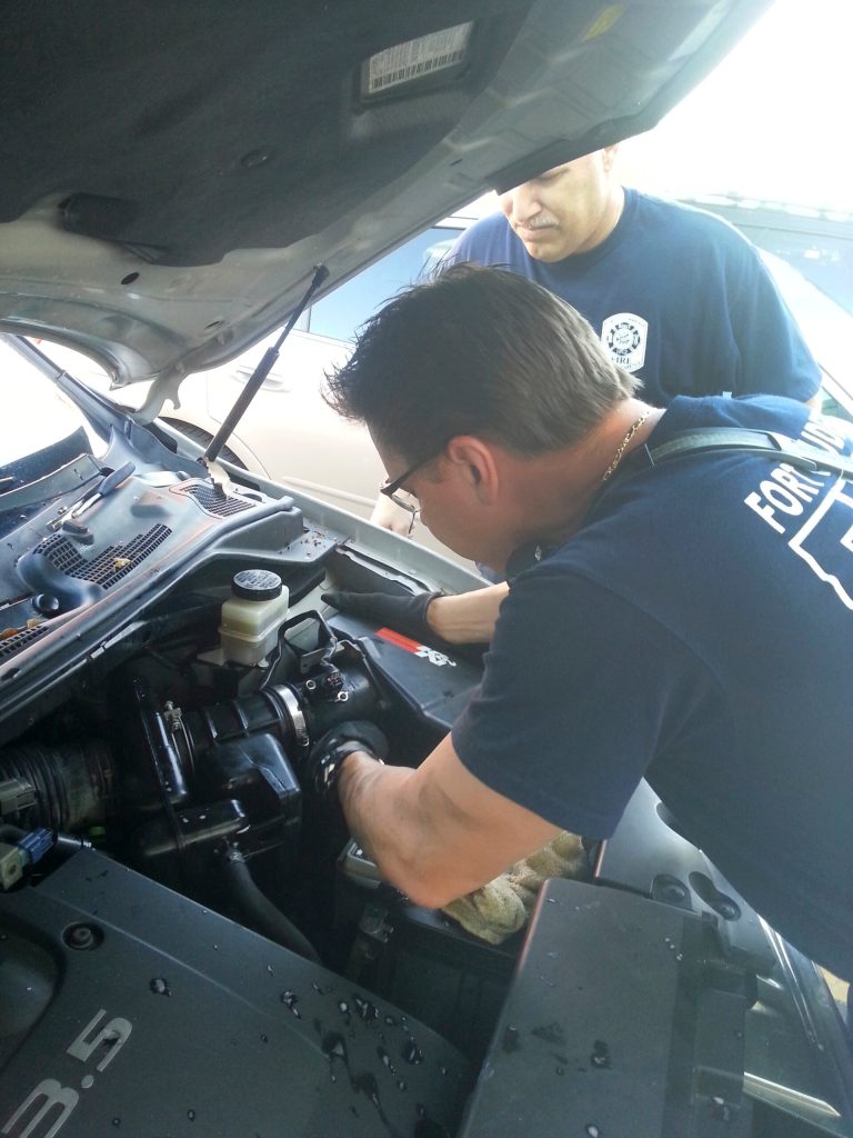 In this Thursday, June 5, 2014 photo provided by Fort Lauderdale Fire Rescue, firefighters work to remove one of two kittens trapped in a car's engine area in Fort Lauderdale, Fla. Firefighters found another in the undercarriage of the vehicle. They were returned unharmed to their owner. (AP Photo/Fort Lauderdale Fire Rescue)