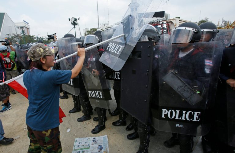 An anti-government protester strikes back at riot police retaking a protest site in Bangkok, Thailand, Friday, Feb. 14, 2014. Riot police cleared anti-government protesters from a major boulevard in the Thai capital in a small victory for authorities Friday as they try to reclaim areas that have been closed during a three-month push to unseat Prime Minister Yingluck Shinawatra. (AP Photo/Wally Santana)