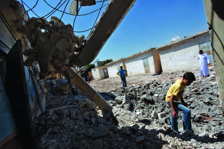 Syrians check the damage of a destroyed school after it was hit by an air strike killing six Syrians in town of Tal Rifat on the outskirts of Aleppo city, Syria, Wednesday, Aug. 8, 2012. In another sign of violence continuing throughout Syria, Syrian fighter jets carried out air strikes early Wednesday on the village of Tel Rifat north of Aleppo, hitting a home and a high school and killing six people from the same family, residents said. (AP Photo/ Khalil Hamra)