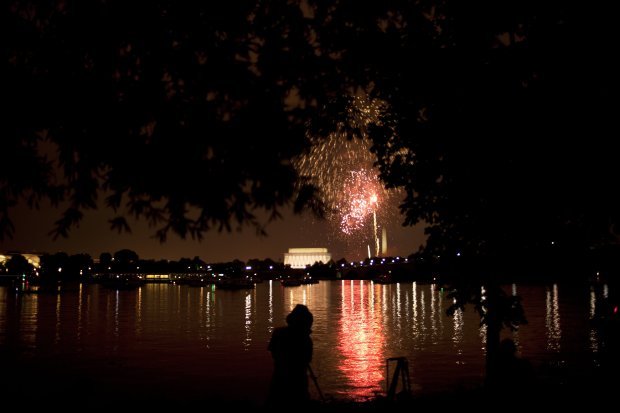 A person watches from Arlington along the shore of the Potomac River as fireworks are shot over the National Mall in Washington on July 4, 2011. (Photo by Brendan Smialowski/Getty Images)
