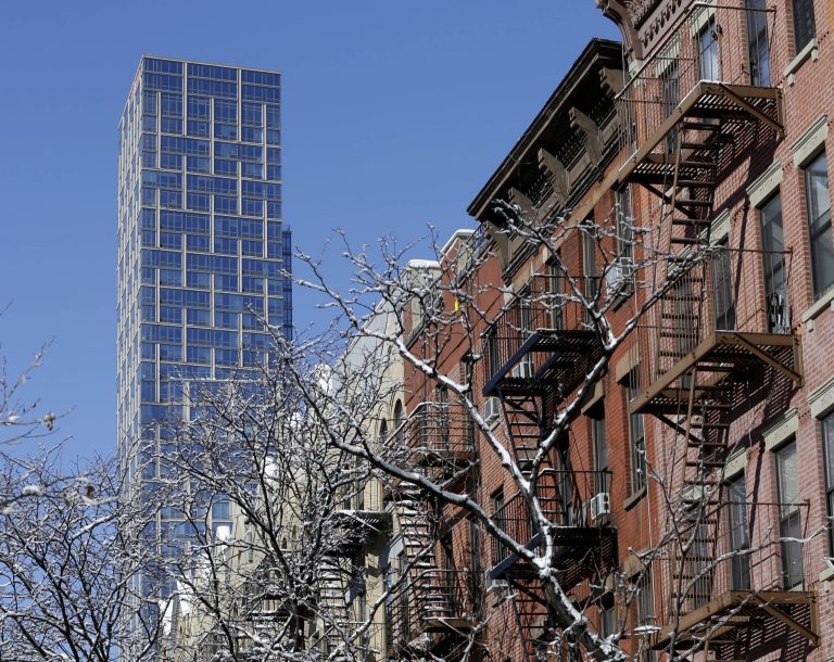 A luxury rental building rises high above other residential buildings in the East Harlem section of New York, Tuesday, Feb. 3, 2015. (AP Photo/Seth Wenig)