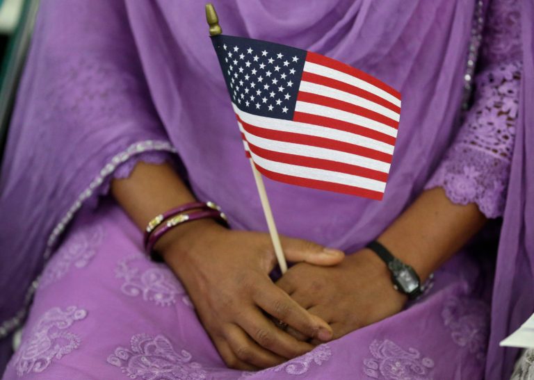 A new U.S. citizen holds an American flag at a naturalization ceremony at the Benjamin Harrison Presidential Site in Indianapolis, Thursday, July 3, 2014.  Judge Sarah Evans Barker naturalized 101 new citizens at the ceremony. The ceremony was part of an annual celebration of Independence Day by U.S. Citizenship and Immigration Services. (AP Photo/Michael Conroy)