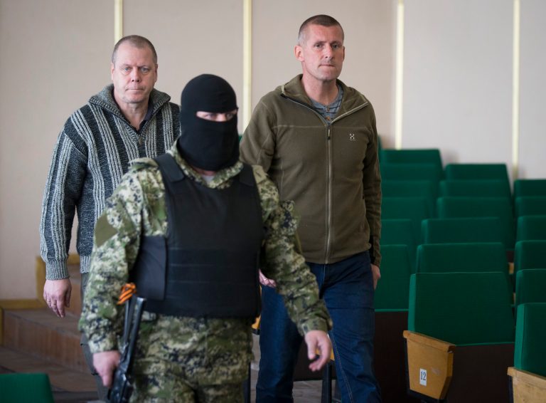 John Christensen, right, a senior Sgt. in the Danish army and his colleague, both members of a group of foreign military observers are escorted by a pro-Russian militant to attend a press conference in the city hall of Slovyansk, eastern Ukraine, Sunday, April 27, 2014. As Western governments vowed to impose more sanctions against Russia and its supporters in eastern Ukraine, a group of foreign military observers remained in captivity Saturday accused of being NATO spies by a pro-Russian insurgency. The German-led, eight-member team was traveling under the auspices of the Organization of Security and Cooperation in Europe when they were detained Friday. (AP Photo/Alexander Zemlianichenko)