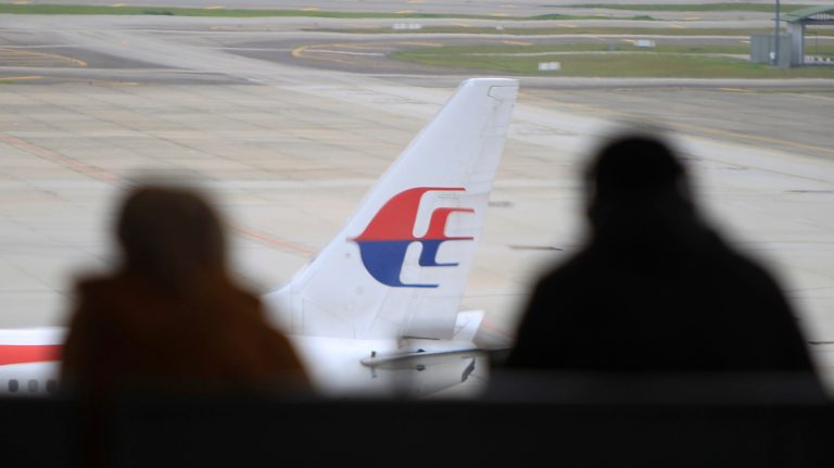 Visitors look out from viewing gallery as a Malaysia Airlines jet sits in the tarmac at the Kuala Lumpur International Airport (KLIA) in Sepang, Malaysia, Friday, Aug. 29, 2014. Malaysia Airlines will cut 6,000 workers as part of an overhaul announced Friday to revive its damaged brand after being hit by double passenger jet disasters. (AP Photo/Lai Seng Sin)