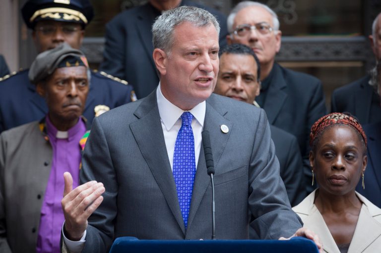 New York City Mayor Bill de Blasio speaks at a press conference alongside First Lady Chirlane McCray, right, following a multi-faith roundtable meeting Wednesday, Aug. 20. (AP/John Minchillo)