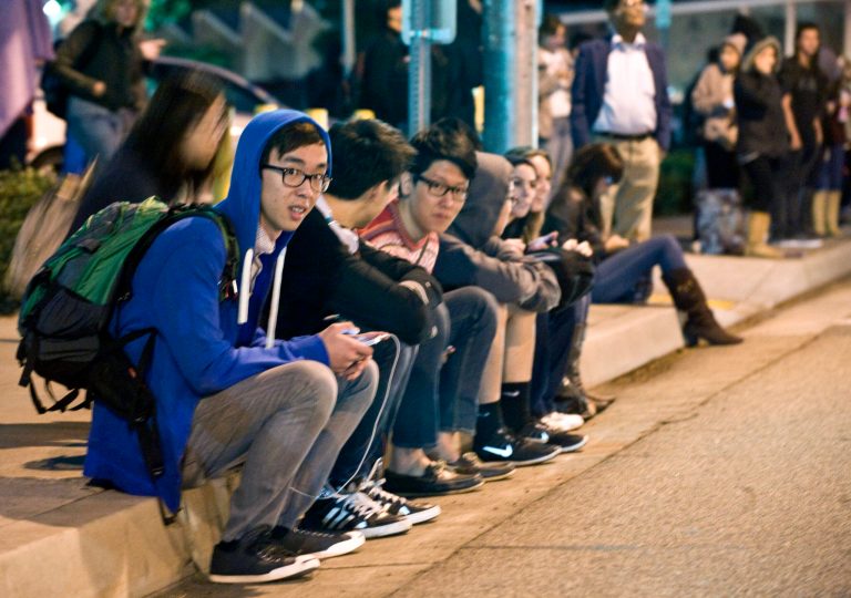   Evacuated students sit on the curb across the street from the Mihaylo College of Business and Economics south of the Cal State Fullerton campus, Wednesday, Dec. 12, 2012, in Fullerton, Calif. Students were placed on lock down as police searched for two suspects in a jewelry store robbery, who were considered armed and dangerous. (AP Photo/The Orange County Register, Bruce Chambers)  