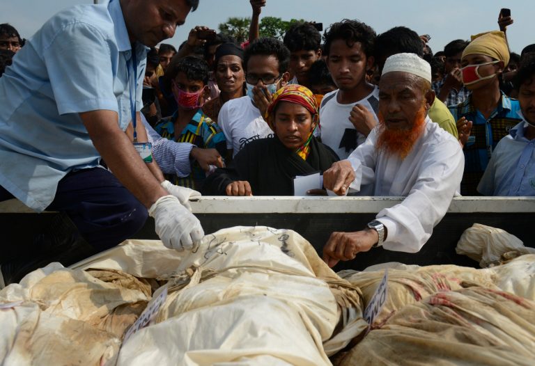 In this photograph taken on Wednesday, May 1, 2013, Farida, center, looks through bodies which arrived at a cemetery in hopes of finding her sister-in-law Fahima in Dhaka, Bangladesh. Just moments before Fahima was to be placed in one of the dozens of unmarked graves dug for victims of Bangladesh's building collapse, Farida was able to claim and leave with her sister-in-law's body. For Farida and countless other relatives of the garment workers who disappeared when Rana Plaza came crashing down, the past week has been one of tumbling expectations, as hope that their loved ones survived faded into the realization that they may have to return home without even a body to bury. (AP Photo/Ismail Ferdous)