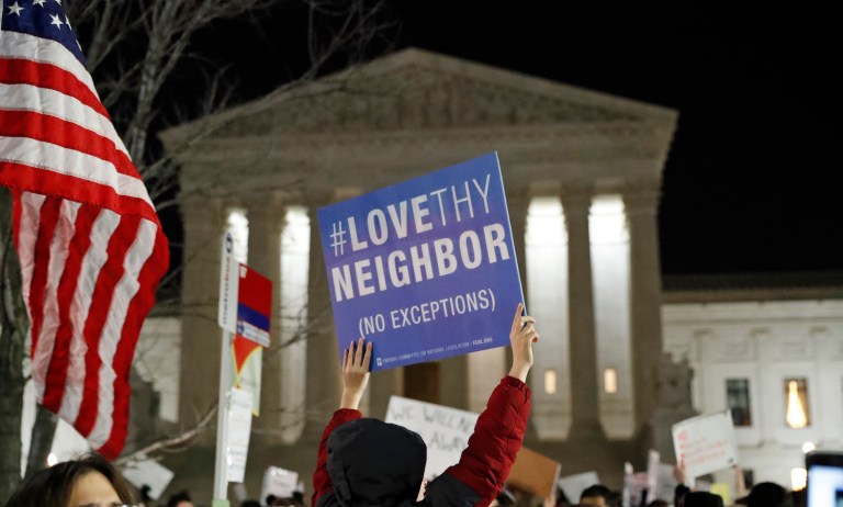 A protester carries a sign in front of the Supreme Court during a protest about President Donald Trump's recent executive orders, Monday, Jan. 30, 2017 in Washington. (AP Photo/Alex Brandon)