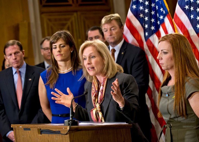 Sen. Kirsten Gillibrand, D-N.Y., is flanked by Sarah Plummer, left, a Marine Corps veteran and victim of sexual assault, and Kate Weber, right, a veteran who was sexually assaulted during her service in the Army, during a news conference on Capitol Hill in Washington, Tuesday, Nov. 19, 2013. They are surrounded by supporters of her proposal to let military prosecutors rather than commanders make decisions on whether to prosecute sexual assaults in the armed forces. At far left is Sen. Richard Blumenthal, D-Conn. Sen. Dean Heller, R-Nev., stands behind Sen. Gillibrand at center. (AP Photo/J. Scott Applewhite)