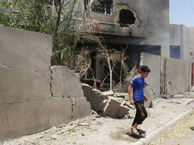 FILE - in this Saturday, July 19, 2014 file photo Abdullah Ahmed walks outside his home that was damaged in a bombing, in Fallujah, 40 miles (65 kilometers) west of Baghdad, Iraq. Iraq's prime minister Haider al-Abadi said Saturday he has ordered the army to stop shelling populated areas held by militants in order to spare the lives of 