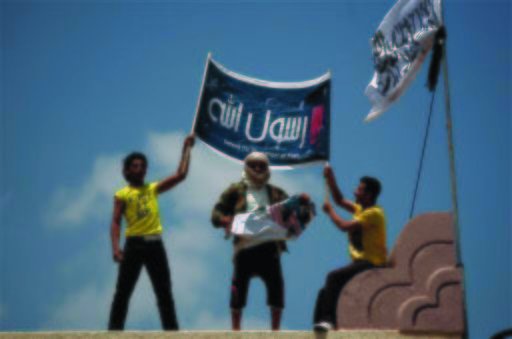 A Yemeni protestor, center, destroys an American flag pulled down as other hold an Islamic banner. (AP Photo/Hani Mohammed)