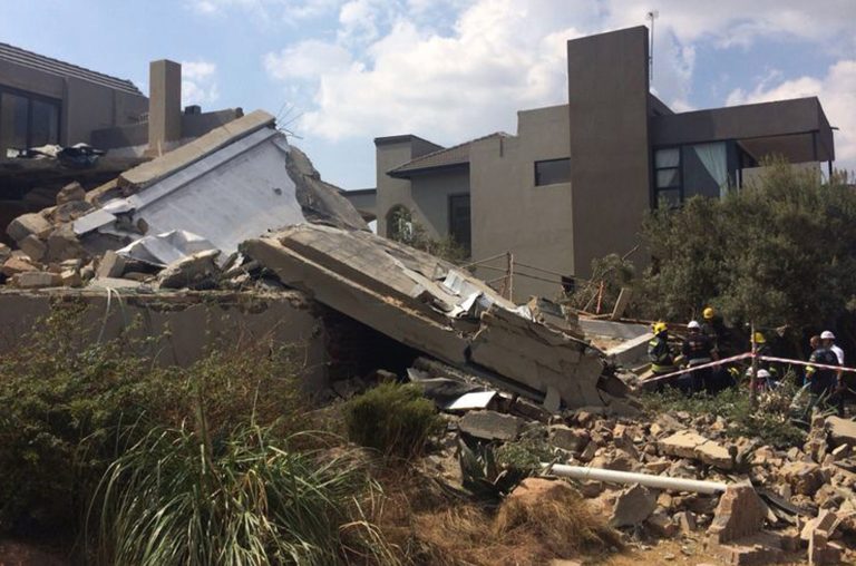 Emergency service workers, on right, attempt to remove bodies of people who were killed when a structure collapsed on a housing building site, south of Johannesburg, Monday, Aug. 18, 2014.  A building under renovation on the site collapsed killing eight, officials said. Another two people were missing. (AP Photo)