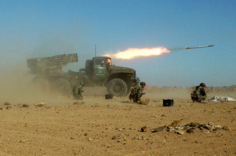 Syrian soldiers kneel next to a multiple rocket launcher as they fire missiles during a maneuver at an unknown location in Syria. (AP/SANA)