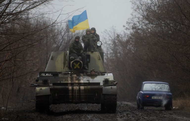 Ukrainian servicemen ride atop an armored vehicle with a Ukrainian flag, on the outskirts of Donetsk, Ukraine, Wednesday, March 4, 2015. (AP Photo/Evgeniy Maloletka)