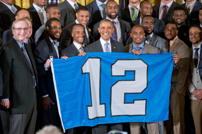 President Barack Obama holds up a '12th man' banner as he welcomes the NFL Super Bowl champion Seattle Seahawks football team to the East Room of the White House in Washington, Wednesday, May 21, 2014. The Seahawks defeated the Denver Broncos in Super Bowl XLVIII. (AP Photo/Pablo Martinez Monsivais)