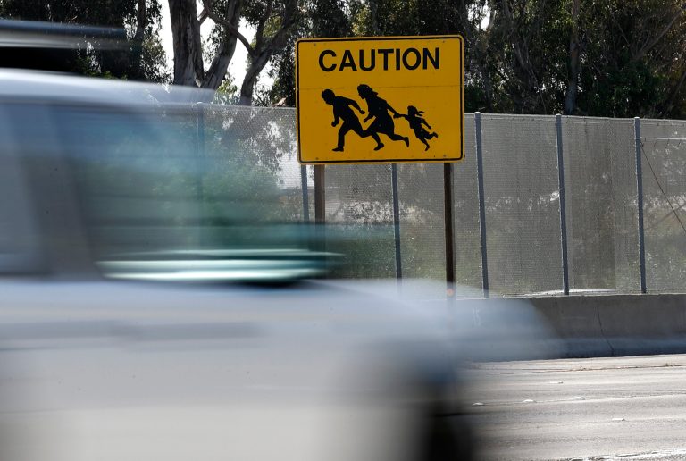Cars pass a sign alerting motorists to watch for people crossing Interstate 5 just north of the border with Tijuana, Mexico, Friday, Aug. 4, 2017, in San Diego. The iconic sign, one of many erected during the early 1990s when illegal immigration numbers surged in the region, is now the last of its kind. (AP Photo/Gregory Bull)