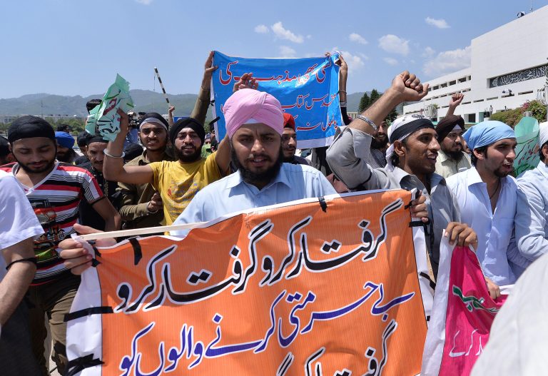 People from Pakistani Sikh community rally in the compound of the parliament in Islamabad, Pakistan, Friday, May 23, 2014. Dozens of baton-wielding Sikhs pushed past the front gate and entered the grounds of Pakistan's parliament Friday, protesting recent attacks on their houses of worship. Banner reads 
