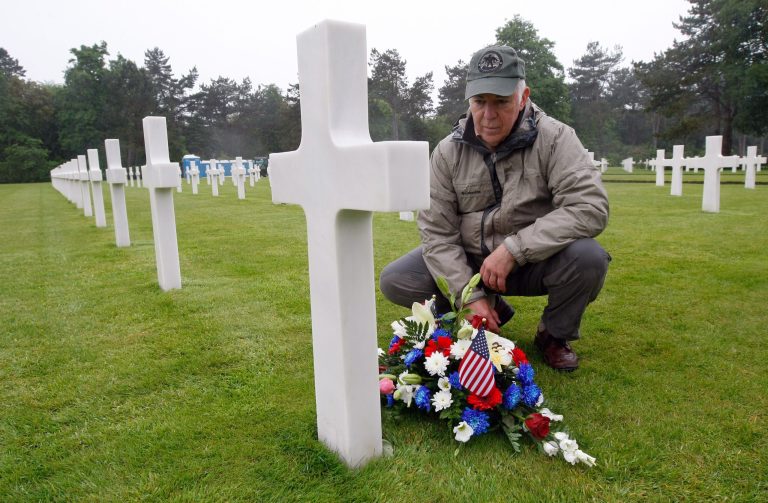 Paul Clifford, 70,  from Boston MA, USA, places flowers on the grave of Walter J. Gunther Jr, the uncle of his best friend, in the Normandy American Cemetery and Memorial, in Colleville sur Mer, France, Wednesday June 4, 2014.  World leaders and veterans prepare to mark the 70th anniversary of the D-Day invasion this week in Normandy. (AP Photo/Claude Paris)