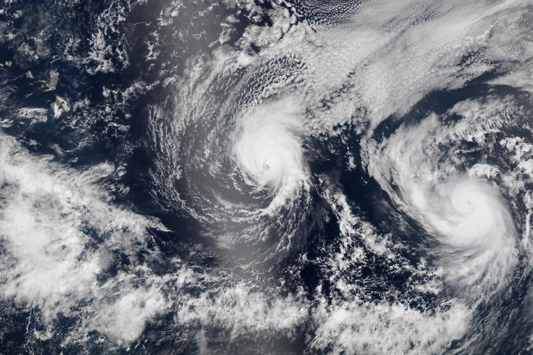 This Aug. 5, 2014 satellite image provided by NASA shows two tropical Pacific Ocean hurricanes - Iselle at center and Julio at right - bearing down on Hawaii, top left. Hurricane Iselle is expected to reach Hawaii Thursday night, Aug. 7, 2014. Tracking close behind it is Hurricane Julio, which strengthened early Thursday into a Category 2 storm. (AP Photo/NASA)