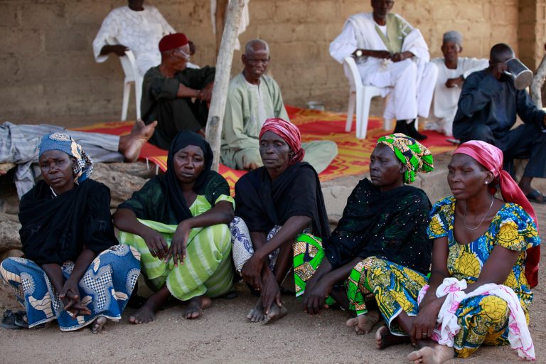 FILE- In this Sunday, May 18, 2014 file photo some of the parents of the kidnapped school girls sit outside a compound during a meeting in Chibok, Nigeria. At least 11 parents of the more than 200 kidnapped Nigerian schoolgirls will never see their daughters again. Since the mass abduction of the schoolgirls by Islamic extremists three months ago, at least 11 of their parents have died and their hometown, Chibok, is under siege from the militants, residents report. Seven fathers of kidnapped girls were among 51 bodies brought to Chibok hospital after an attack on the nearby village of Kautakari this month, said a health worker who insisted on anonymity for fear of reprisals by the extremists. At least four more parents have died of heart failure, high blood pressure and other illnesses that the community blames on trauma due to the mass abduction 100 days ago, said community leader Pogu Bitrus, who provided their names.  (AP Photo/Sunday Alamba, File)