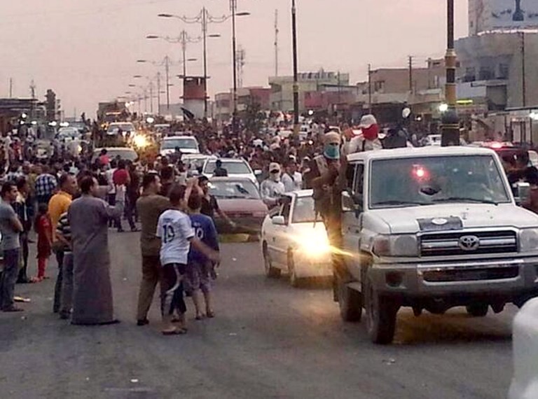 In this still image posted on a militant Twitter account on Wednesday, June 11, 2014, which has been authenticated based on its contents and other AP reporting, militants parade down a main road in Mosul, Iraq.  Iraqi officials say al-Qaida-inspired militants who this week seized much of the country's Sunni heartland have pushed into an ethnically mixed province northeast of Baghdad, capturing two towns there.(AP Photo/militant source via Twitter)