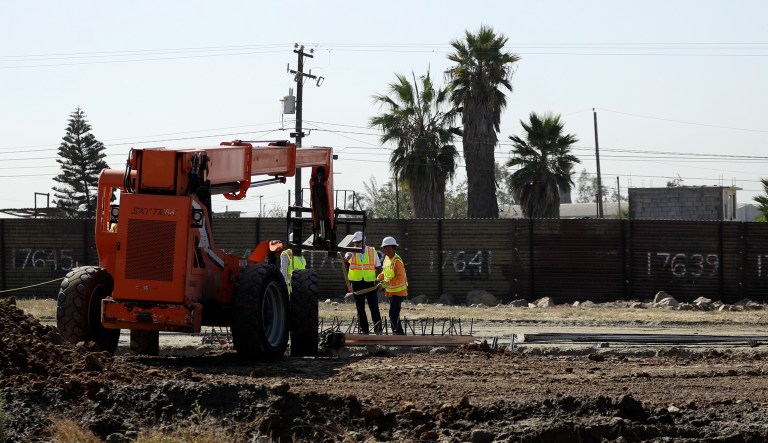 Construction crews work on prototypes for a proposed border wall in front of the primary border structure separating Tijuana, Mexico, behind, and San Diego, Wednesday, Sept. 27, 2017, in San Diego. The federal government is giving a first peek at construction of prototypes for President Donald Trump's proposed border wall, an area that is walled off from public viewing in a remote area of San Diego. (AP Photo/Gregory Bull)