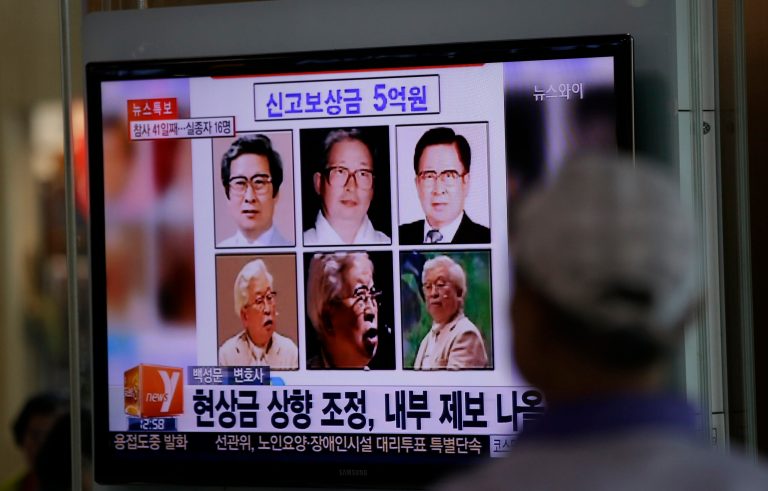 A man watches a TV news program on the reward poster of Yoo Byung-eun at the Seoul Train Station in Seoul, South Korea,  Monday, May 26, 2014. South Korea has boosted to half a million dollars a reward for tips about the mysterious billionaire who prosecutors say owns a ferry that sank last month, police said Monday. (AP Photo/Lee Jin-man)