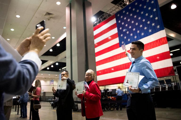 FILE - In this Wednesday, Feb. 15, 2017, file photo, Erik Danialian, a 21-year-old immigrant from Iran, poses with his U.S citizenship certificate in front of a large U.S. flag after a naturalization ceremony at the Los Angeles Convention Center, in Los Angeles. Since Trump's immigration enforcement order and travel ban, immigrants have been rushing to prepare applications to become Americans. Advocates in Los Angeles, Maryland and New York catering to diverse immigrant communities from Latin America, Asia and the Middle East all said they've been fielding a rising number of questions about how to become a U.S. citizen. (AP Photo/Jae C. Hong, File)