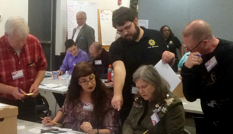 Election officials in Newport News, Va., examine ballots that a computer failed to scan during a recount for a House of Delegates race on Tuesday, Dec. 19, 2017. A three-judge panel unanimously agreed the ballot in question was a vote for Republican David Yancey, overturning a recount that occurred Tuesday and left Democrat Shelly Simonds ahead by a single vote. (AP Photo/Ben Finley)