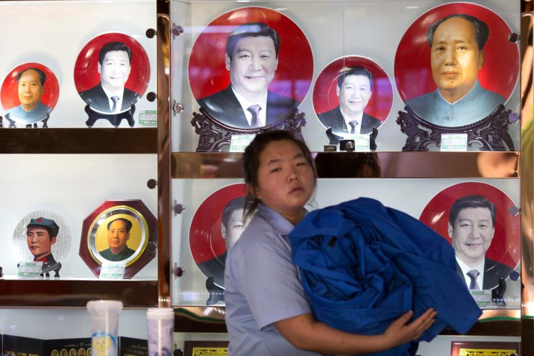 In this photo taken Wednesday, June 4, 2014, a sales person walks past commemorative plates featuring Chinese President Xi Jinping and former supreme leader Mao Zedong at a souvenir stall in Beijing, China. Xi's recent ouster of one of China's top military figure and forceful style of leadership had prompted suggestions he might be trying to roll back the consensus-oriented leadership of the past two decades and restore rule by a dominant strongman. But experts say collective leadership is here to stay because the ruling party is wary of returning to the turbulence China endured under the former supreme leader Mao Zedong. (AP Photo/Ng Han Guan)