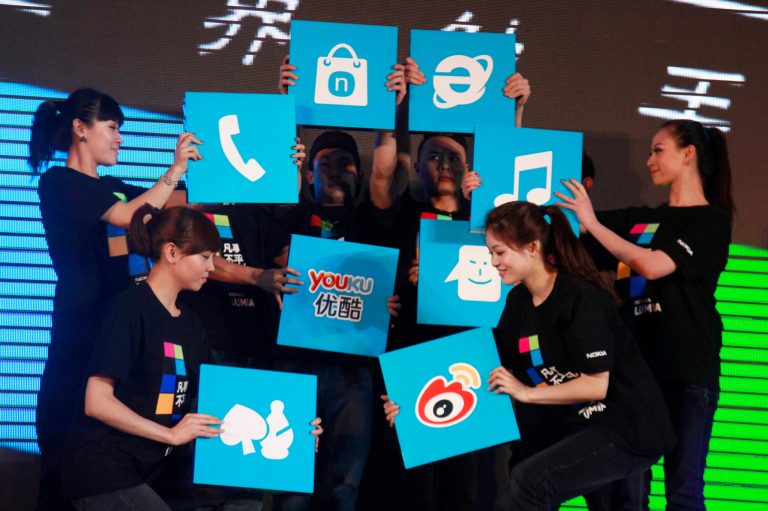 In this photo taken Wednesday, March 28, 2012, Chinese performers hold up cards showing the various apps available for online users for shopping and other services at the launch of a mobile phone in Beijing, China. As Chinaâs 600 million-plus Web surfers migrate abruptly to going online via smartphone or tablet, Internet companies are racing to keep up, spending billions of dollars to roll out cheaper, more convenient services. (AP Photo/Ng Han Guan)
