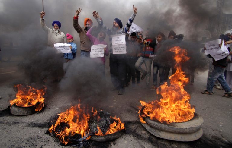 FILE - In this Sunday, Feb. 2, 2014 file photo, Indian Sikh protesters shout slogans and burn tires during a protest against Congress party leader Rahul Gandhi for his recent remark on the country's 1984 anti-Sikh riots, in Jammu, India. India has blocked the release of a film on the assassination of former Indian Prime Minister Indira Gandhi, Rahul's grandmother, saying it glorifies her killers and could trigger violent protests, officials said Friday, Aug. 22, 2014. India's film certification board said the film glorified the two Sikh bodyguards who killed Gandhi to avenge her suppression of an insurgency that culminated in an army assault on the Golden Temple, Sikhism's holiest shrine. (AP Photo/Channi Anand, File)