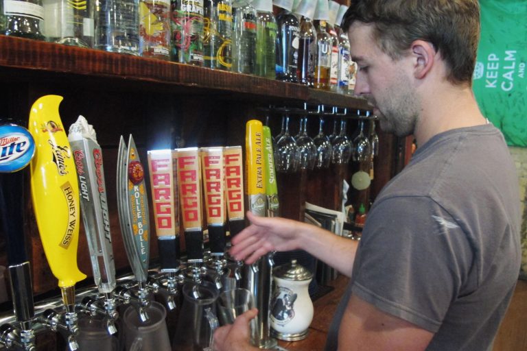 FILE - In this July 23, 2013 file photo, Ian Dickmeyer, general manager at Rhombus Guys pizza in downtown Fargo, N.D., pours a Fargo Brewing Co. beer. Dickmeyer says he keeps four of the company's beers on tap at all time. Four MBA students from Columbia are working with the Fargo Brewing Co. on the perception of the company brand and potential markets for expansion. (AP Photo/Dave Kolpack, File)