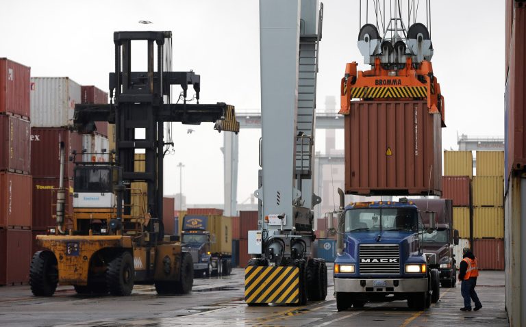   In this photo taken Tuesday, Dec. 18, 2012, a truck driver watches as a freight container, right, is lowered onto a tractor trailer truck by a container crane at the Port of Boston, in Boston. The crane and a reach stacker, left, are operated by longshoremen at the port. The longshoremen's union may strike if they are unable to reach an agreement on their contract that expires Dec. 29, 2012. (AP Photo/Steven Senne)  