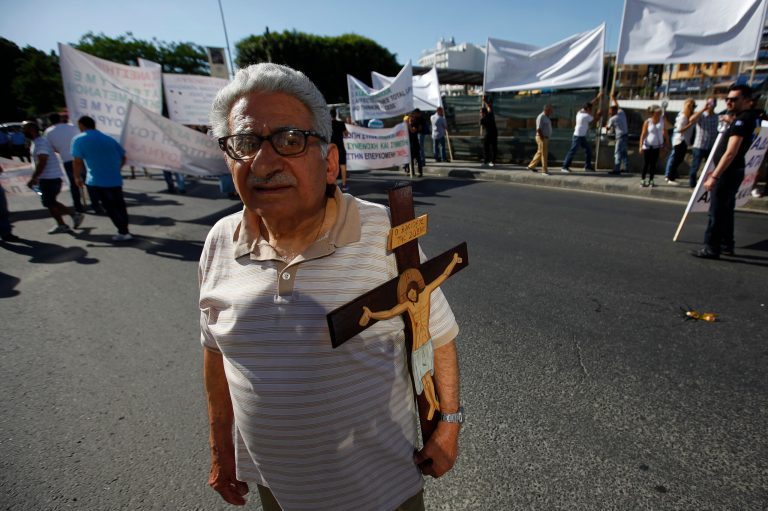 An Christian Orthodox holds a cross as he joins the small group of Orthodox Christian protesters staged near the first gay pride parade in downtown Nicosia, Cyprus, Saturday, May 31, 2014. Several thousand people have turned out for Cyprus' first gay pride parade, an event which organizers say show that Cypriots are shedding their conservative views. One of the organizers, Costas Gavrielides, said he had initially hoped for just a few hundred people to attend the event in the heart of the capital Nicosia on Saturday. A small group of Orthodox Christian protesters in the east Mediterranean island nation staged a demonstration nearby to denounce the event they called 