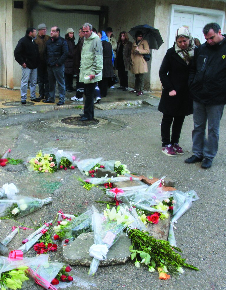 People look at the flowers placed at the site, just outside his home, where opposition leader Chokri Belaid was killed, Thursday Feb. 7, 2013 in Tunis. Tunisia's opposition parties on welcomed the government's move to dissolve itself in favor of a caretaker body following the shocking assassination of a leftist politician. The Wednesday assassination of prominent government critic Chokri Belaid plunged the country into one of its deepest political crises since the overthrow of the dictatorship in 2011. (AP Photo/Amine Landoulsi)