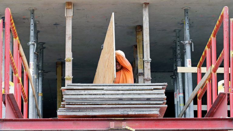 In this photo taken July 22, 2014, a construction worker carries a sheet of plywood at the site of a 36-floor high rise condominium in Miami. The National Association of Home Builders reports on sentiment among U.S. builders on Monday, Aug. 18, 2014. (AP Photo/Alan Diaz)