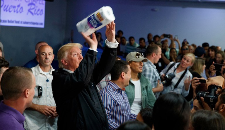 President Donald Trump tosses paper towels into a crowd as he hands out supplies at Calvary Chapel, Tuesday, Oct. 3, 2017, in Guaynabo, Puerto Rico. Trump is in Puerto Rico to survey hurricane damage. (AP Photo/Evan Vucci)