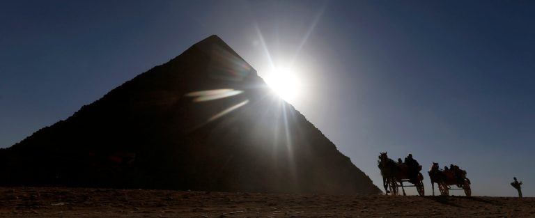   Tourists ride in horse carriages past one of the Great Pyramids in Giza, Egypt, Wednesday, Dec. 12, 2012. An Egyptian opposition alliance urged supporters on Wednesday to vote 