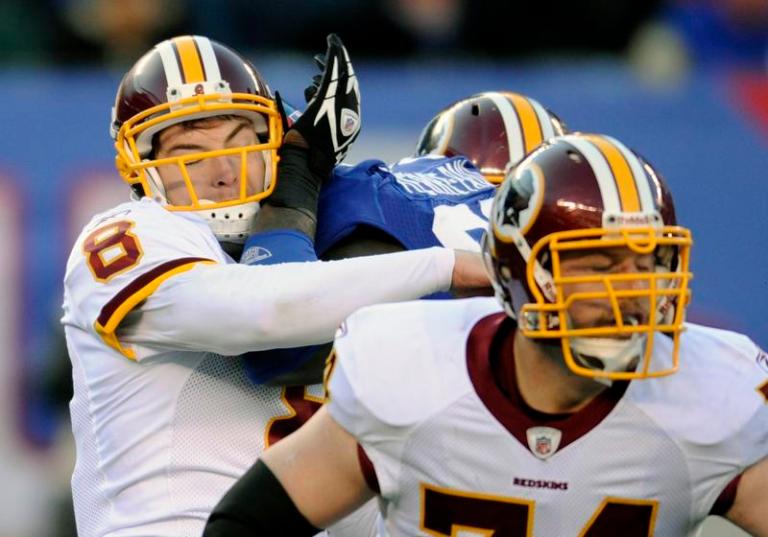 Washington Redskins' Rex Grossman, left, is hit by New York Giants' Jason Pierre-Paul, center, during the second quarter on Sunday in East Rutherford, N.J. Pierre-Paul was penalized for roughing the passer. The Redskins defeated the Giants 23-10.
