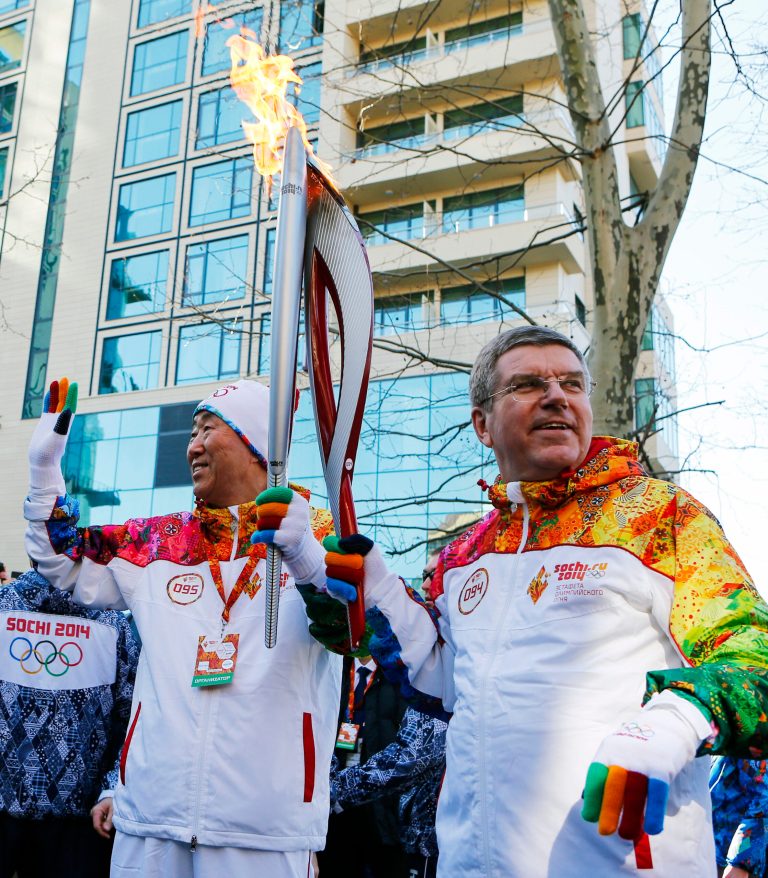 IOC President Thomas Bach, right, hands over the Olympic torch to United Nations Secretary-General Ban Ki-moon as the torch relay arrives in Sochi,  ahead of the 2014 Winter Olympics, Thursday, Feb. 6, 2014, in Russia.  (AP Photo/Shamil Zhumatov, Pool)